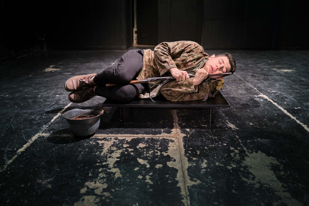 Szene aus Theaterstück: Soldat kauert auf dem Boden.